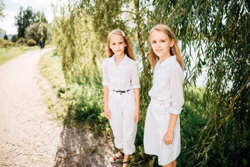 little children play in the park, two girls with long hair have rest outdoors