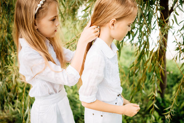 little children play in the park, two girls with long hair have rest outdoors