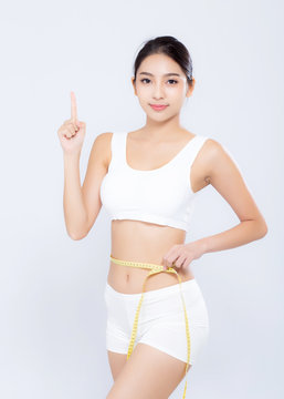 Beautiful asian woman diet and slim with measuring waist for weight finger pointing something isolated on white background, girl have cellulite loss with tape measure, health and wellness concept.
