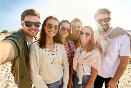 friendship, leisure and people concept - group of happy friends taking selfie on beach in summer