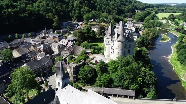 Aerial 4K, drone flying around old town and Castle in Durbuy, Belgium, surrounded by mountains, river and kayakers on the river in green kayaks paddling in a beautiful green scenery in summertime