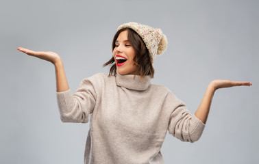 christmas, season and people concept - happy smiling young woman in knitted winter hat and sweater...