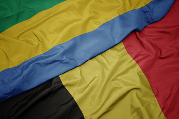waving colorful flag of belgium and national flag of gabon.