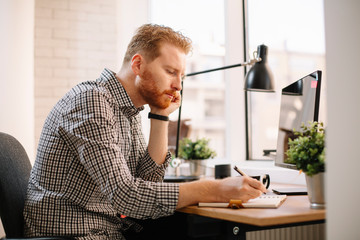 Fototapeta premium Businessman taking notes. Young man writing in notebook.