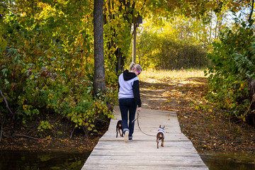 Blond woman walking her dog in a trail at fall