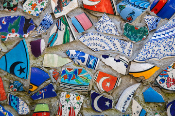 Mosaic of broken tiles wall in Istanbul, wall made of colorful mosaic broken tiles Turkey. Splinters of a white ceramic tile on cement. Texture pieces against a dark background. Mosaic on the wall