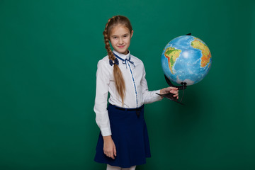 Schoolgirl girl studies globe at school on geography