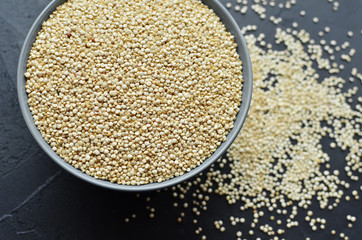 Dry organic quinoa seeds in ceramic bowl on dark grunge background