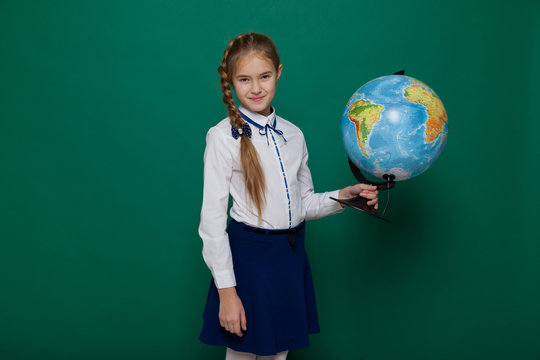 Schoolgirl girl studies globe at school on geography