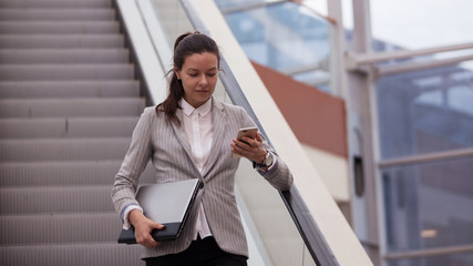 Young businesswoman with glasses and a phone in her hands. In the office or business center.