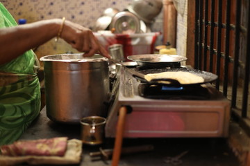 The woman standing next to stove and preparing dinner in the kitchen. Preparation of Indian food concept.