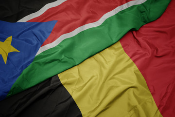 waving colorful flag of belgium and national flag of south sudan.