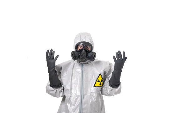 A man poses in a gray protective suit, with a protective gas mask, posing while standing on a white background, holding his hands up in protective gloves. Environmental protection. 