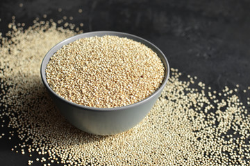 Dry organic quinoa seeds superfood in ceramic bowl on dark concrete background