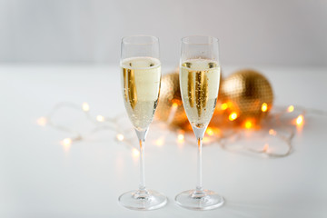 christmas, holidays and celebration concept - two glasses of champagne and decorations