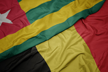 waving colorful flag of belgium and national flag of togo.