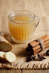 Ginger tea in a glass with fresh sliced ginger and cinnamon