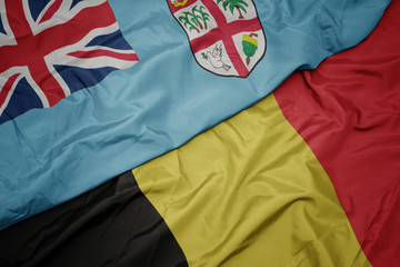 waving colorful flag of belgium and national flag of Fiji .
