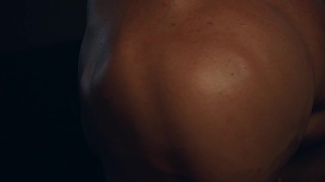 Fitness tanned guy showing muscles of shoulder, close up