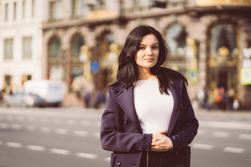 Fototapeta premium Portrait f beautiful intelligent brunette who walks down street of Saint-Petersburg in city center. Charming thoughtful woman with long dark hair wanders alone, immersed in thoughts