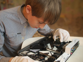 Teenager genius assembles the computer. Close-up of boy installation a central processing unit into a socket on computer mainboard. Working and education.