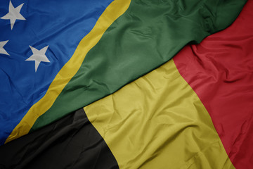 waving colorful flag of belgium and national flag of Solomon Islands .
