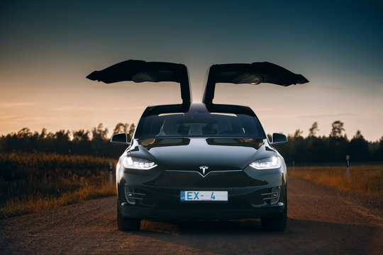  Tesla Model X P100D with falcon wings doors open in the evening. Tesla silhouette, front view. Expensive and luxury electric crossover car