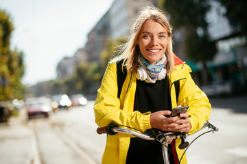 Beautiful woman with bicycle. Young woman using phone.	