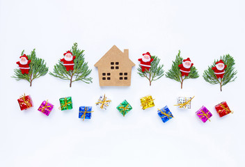 Merry Christmas and Happy Holidays, Miniature house with Christmas composition. gifts, pine branches and decorations on white background.