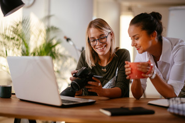 Young woman showing colleague pictures in camera on coffee break