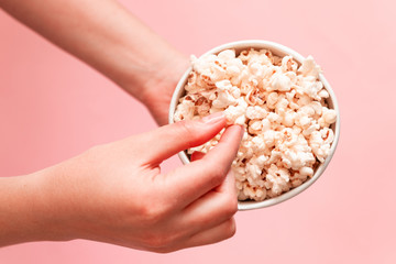 Woman eating popcorn on pink background top view copy space