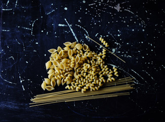 pasta of different shapes on a dark background