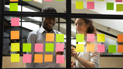 Multiracial colleagues developing business ideas use post-it notes