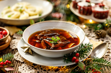 Christmas mushroom soup, a traditional vegetarian  mushroom soup made with dried forest mushrooms in a ceramik plate on a festive table. Polish Christmas dinner
