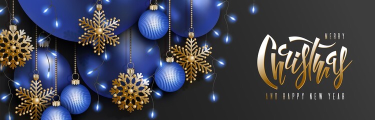 Christmas and 2020 New Year vector design. 3D blue realistic christmas balls, decorative golden snowflakes hang on gold chains, garland of light bulb, hand lettering inscription on black background - 295851602