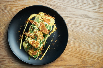 Appetizing and large toast with poached egg, salmon, arugula and cream sauce on a black plate. Healthy Breakfast seafood