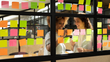Friendly mates discuss business ideas writing its on sticky notes
