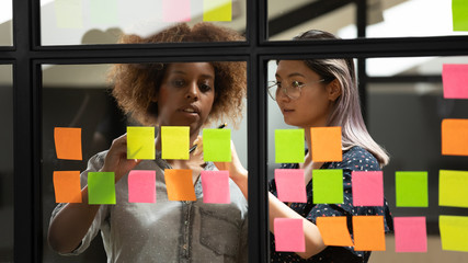 Diverse business women writing plan and ideas using sticky notes