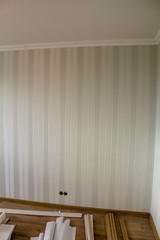 A wall with striped Wallpaper in an empty room with ongoing repairs