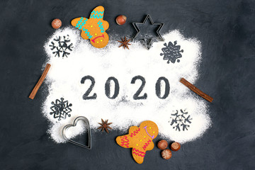 2020 text made with flour with decorations on a black background. Flat lay. Merry Christmas, happy New year concept. Ingredients for making gingerbread