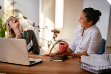 Two young women having coffee break in office