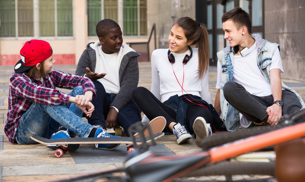 girl and three boys hanging out outdoors and discussing something