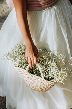 Attractive blond girl in forest dressed in communion with a flower basket