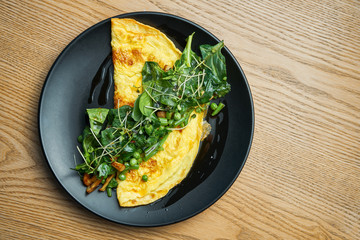 Frittata with mushrooms pesto sauce, arugula and peas on black plate. Tasty and healthy lunch. Omelette