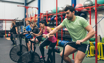 Group of athletes doing air bike at the gym
