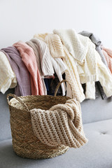 Categorizing winter laundry concept. A messy pile of kniwear lying on grey textile sofa. Bunch of unfolded sweaters prepeared for sorting. Close up copy space, background.