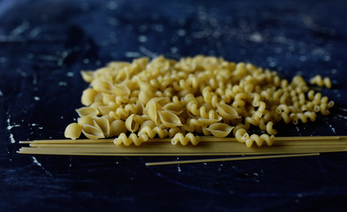 pasta of different shapes on a dark background
