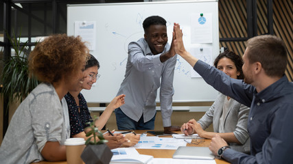 African and Caucasian executives giving high five during group meeting