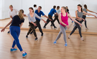 diligent teenage boys and girls learning in dance hall