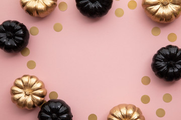 Gold and black pumpkins on pastel pink. Flat lay thanksgiving composition